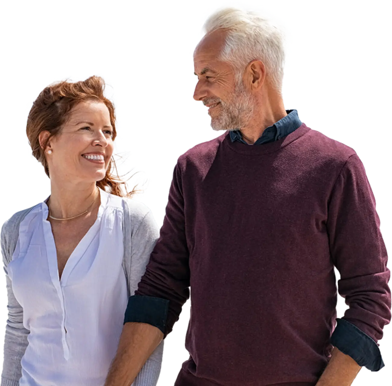 A couple walking, holding hands, and smiling at each other.